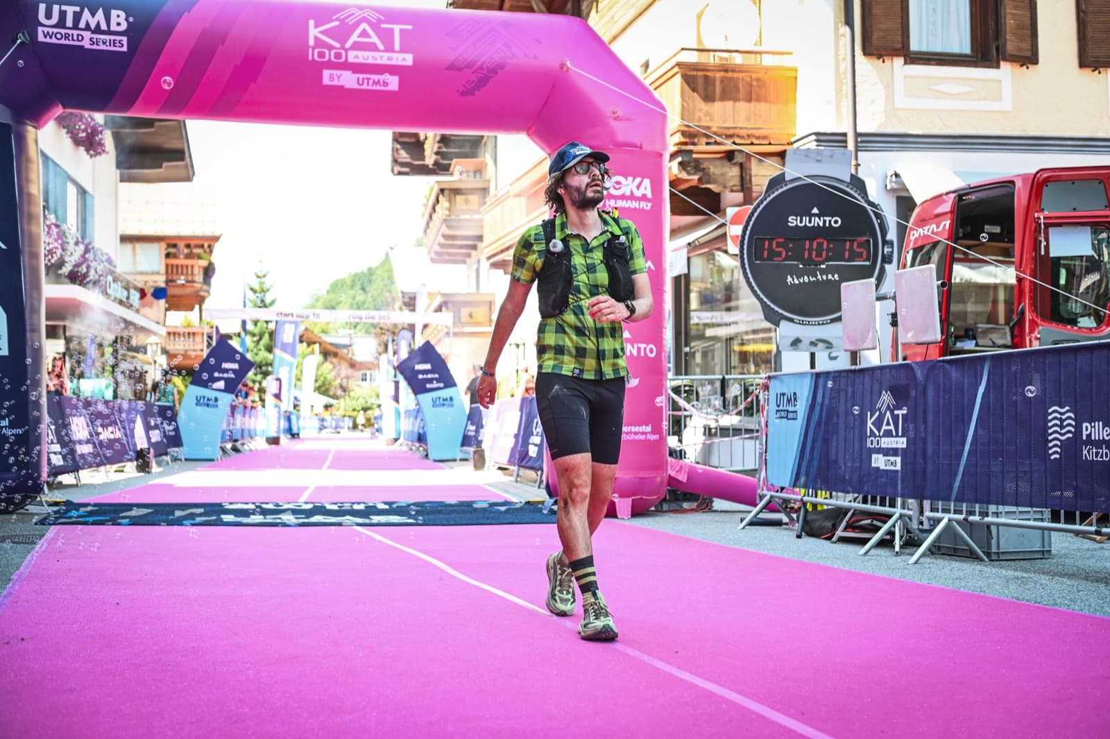 Luis walks to the finish line of KAT100 in Austria, on a pink carpet under the race arch.