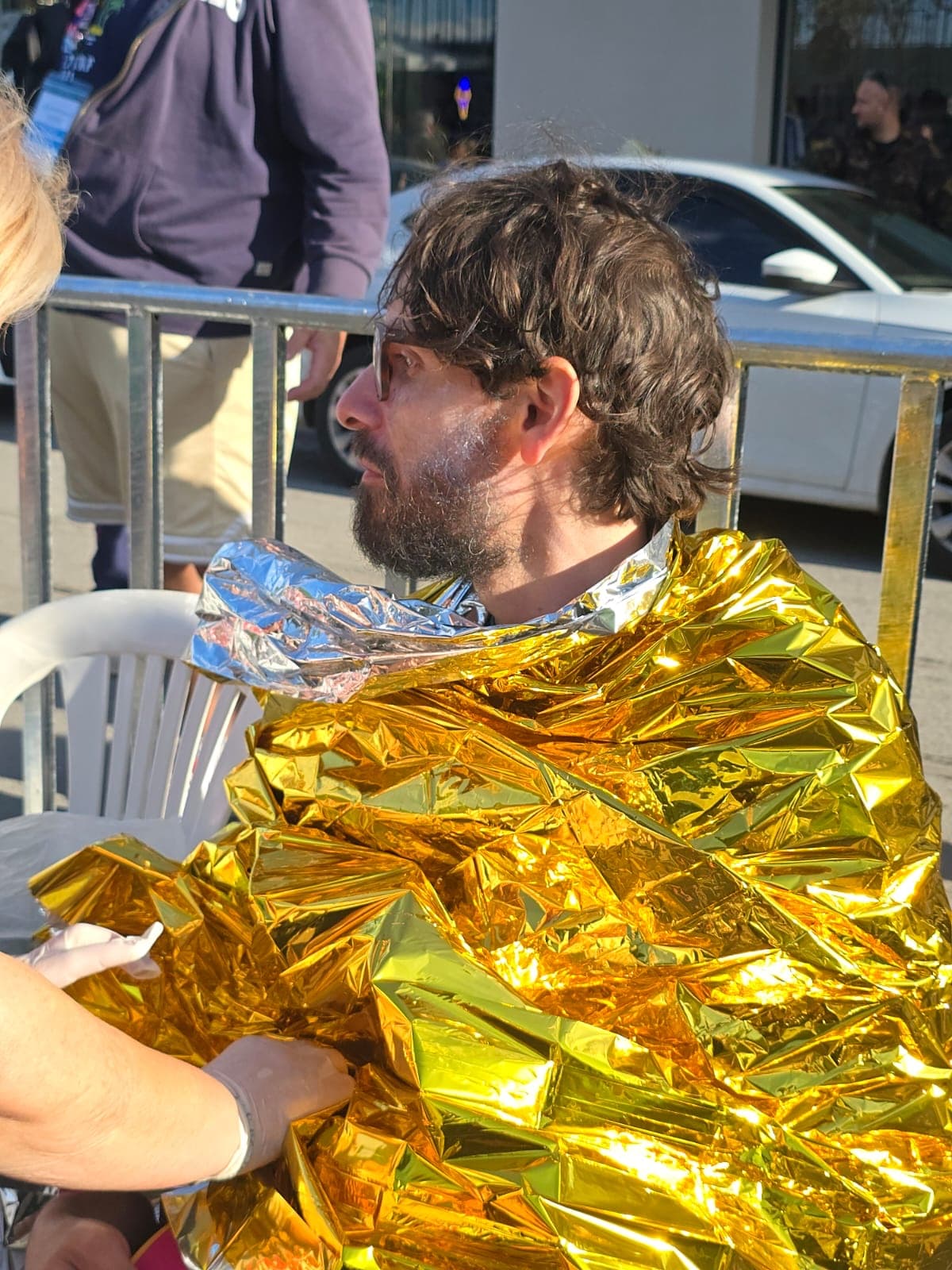 The author sits after the finish, wrapped in a gold thermal blanket, his face tired.