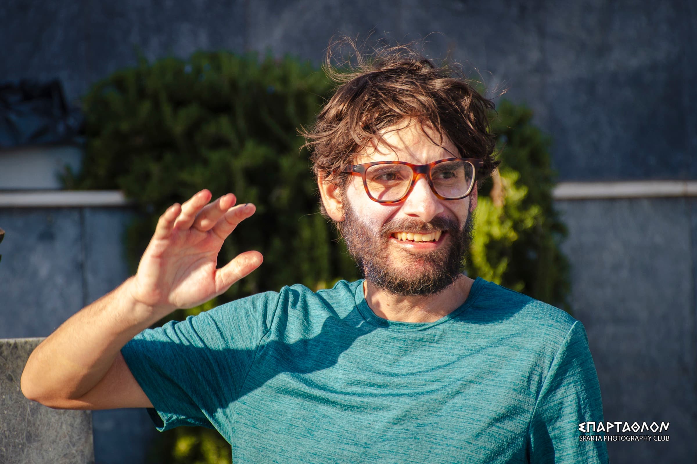 The author at the finish, hair messy and smiling, in a teal shirt, raises his hand to wave.